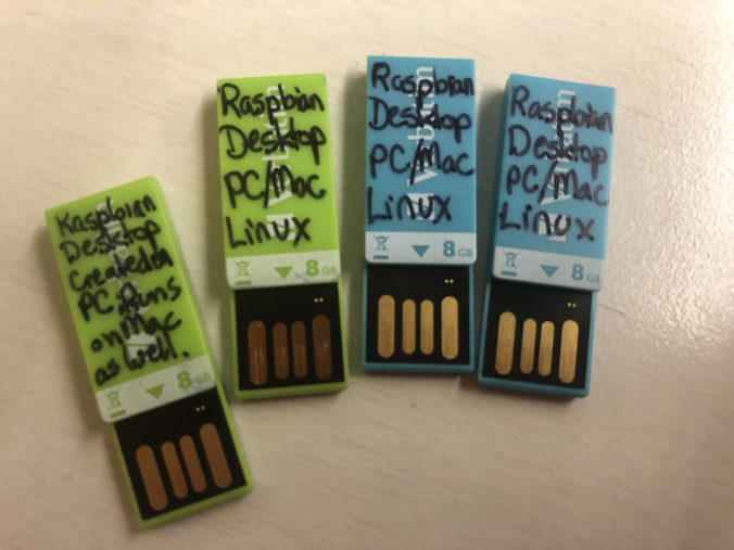 Photo of four brightly colored small USB drives labelled as Raspbian Desktop dual bootable drives